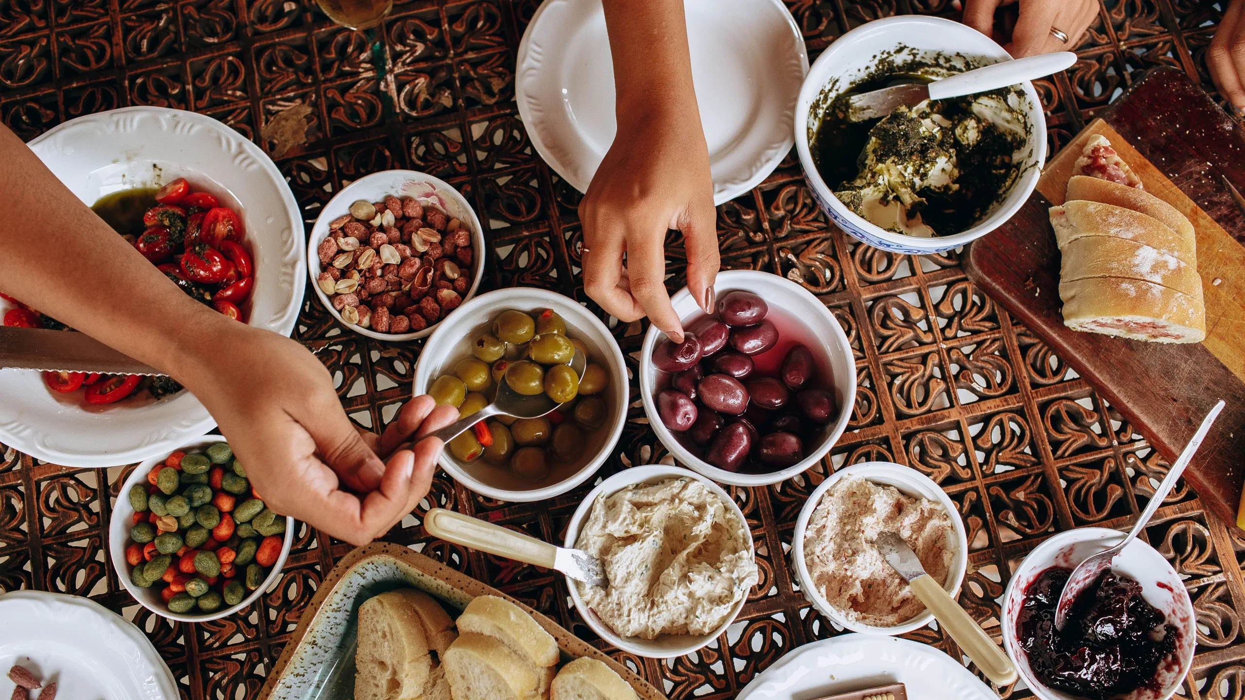 Table de famille dressée : petits plats à partager, olives, pain et salades